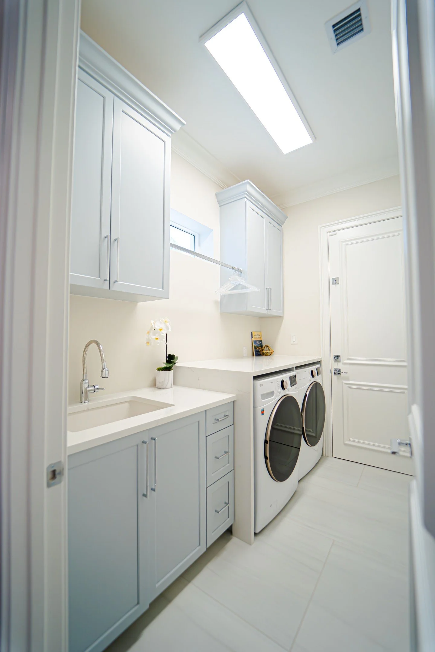 This laundry room is both stylish and highly functional, with sleek cabinetry and tons of storage to keep everything organized. The built-in sink and counter space make chores a breeze, while the soft color palette keeps the space feeling bright and 