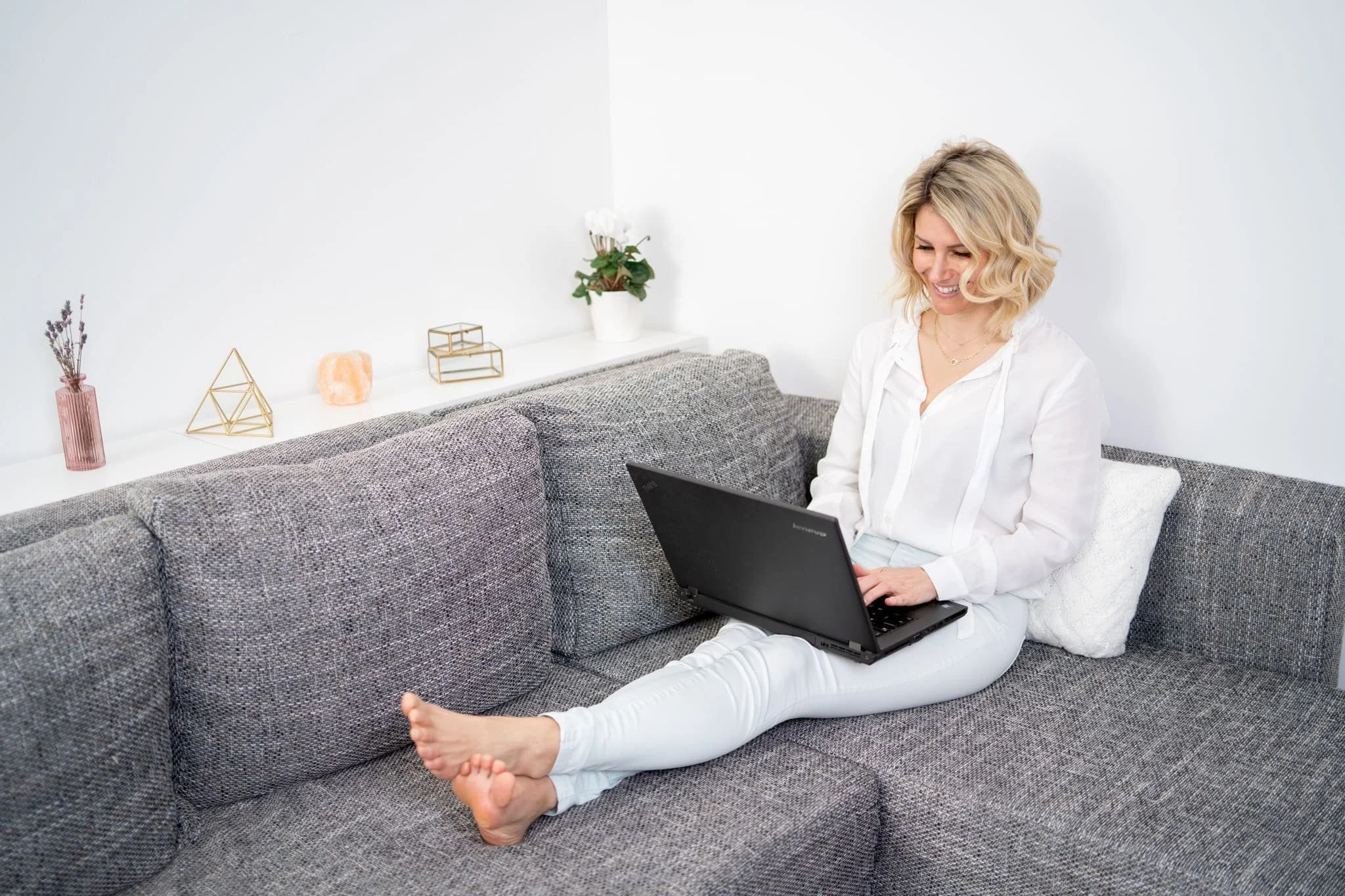 Photo of Rebecca Michelle, a mindfulness meditation coach sitting on a couch with a laptop.
