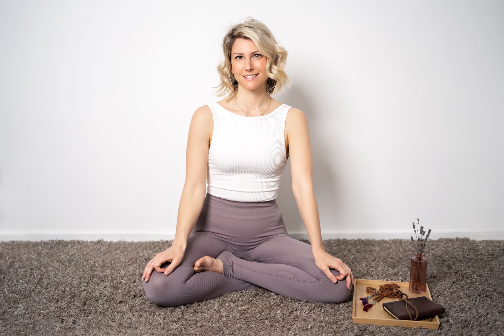 Photo of Rebecca Michelle, meditation coach sitting cross legged smiling.
