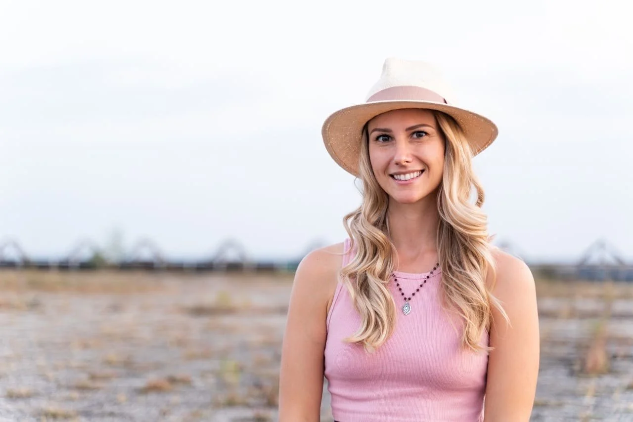 Photo of Rebecca Michelle, an online meditation coach, with a hat on smiling outside.