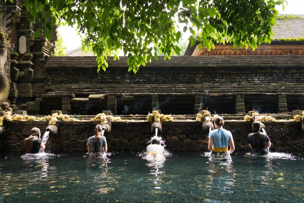 personal meditation coach, rebecca michelle, at a water temple in bali, she is under the water spout with 4 others who are doing the same