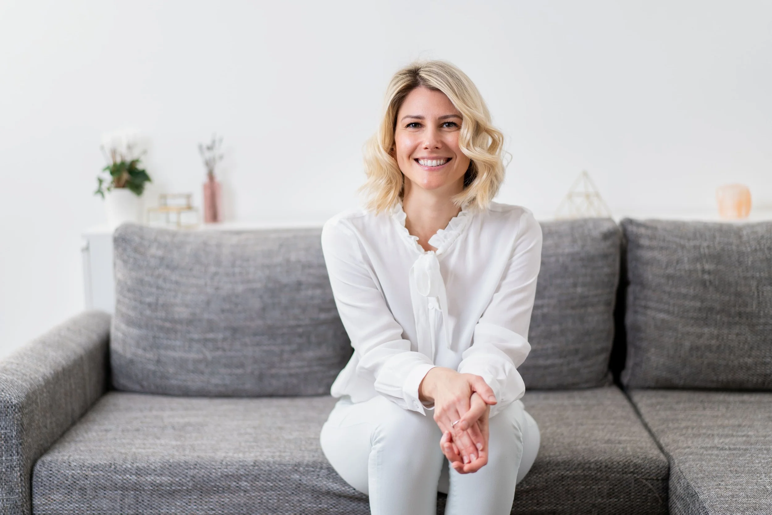 Photo of Rebecca Michelle, a personal meditation coach sitting on a couch with a cup in her hand.