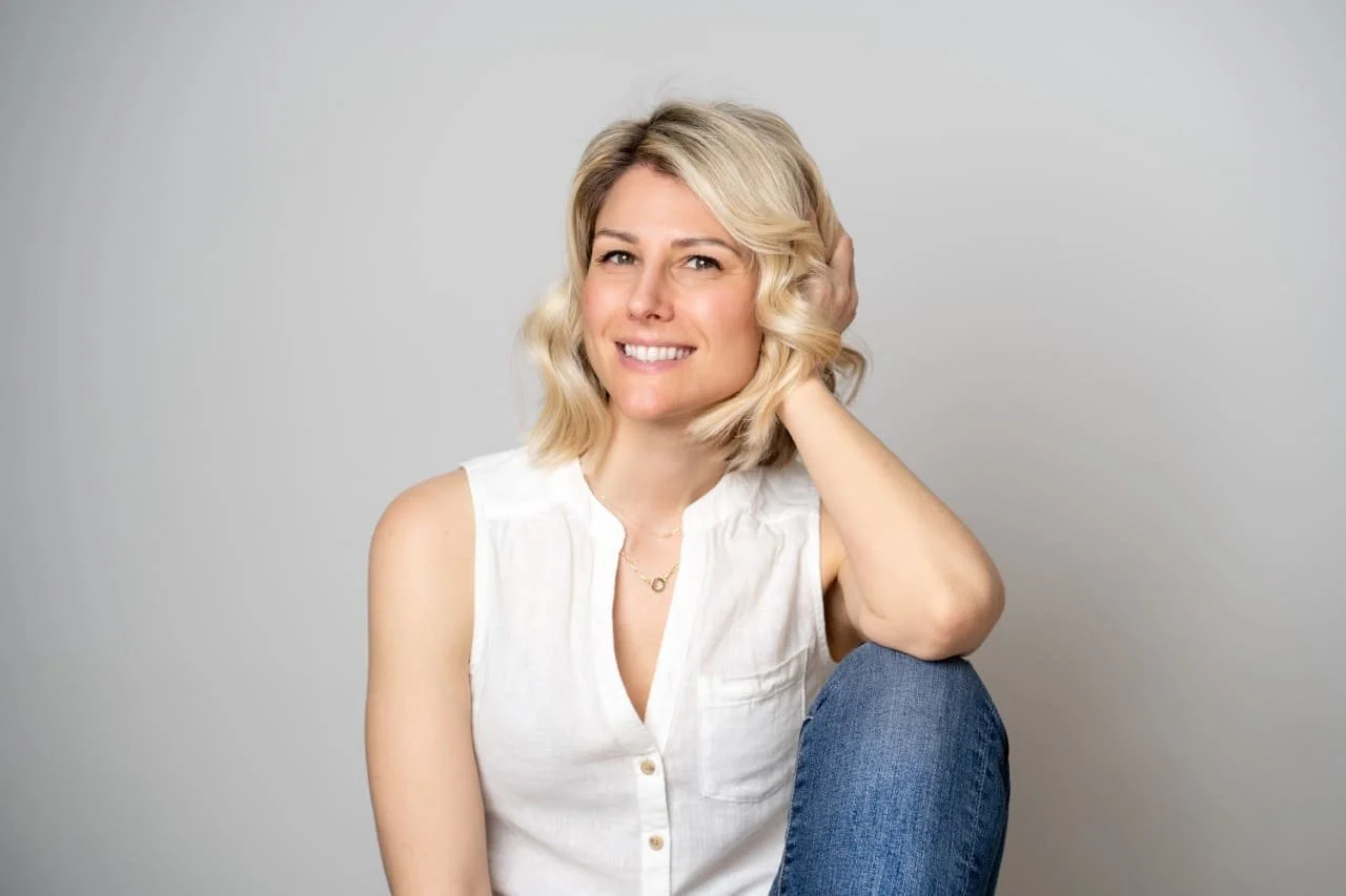 Photo of Rebecca Michelle, a mindfulness meditation coach sitting on a chair smiling.