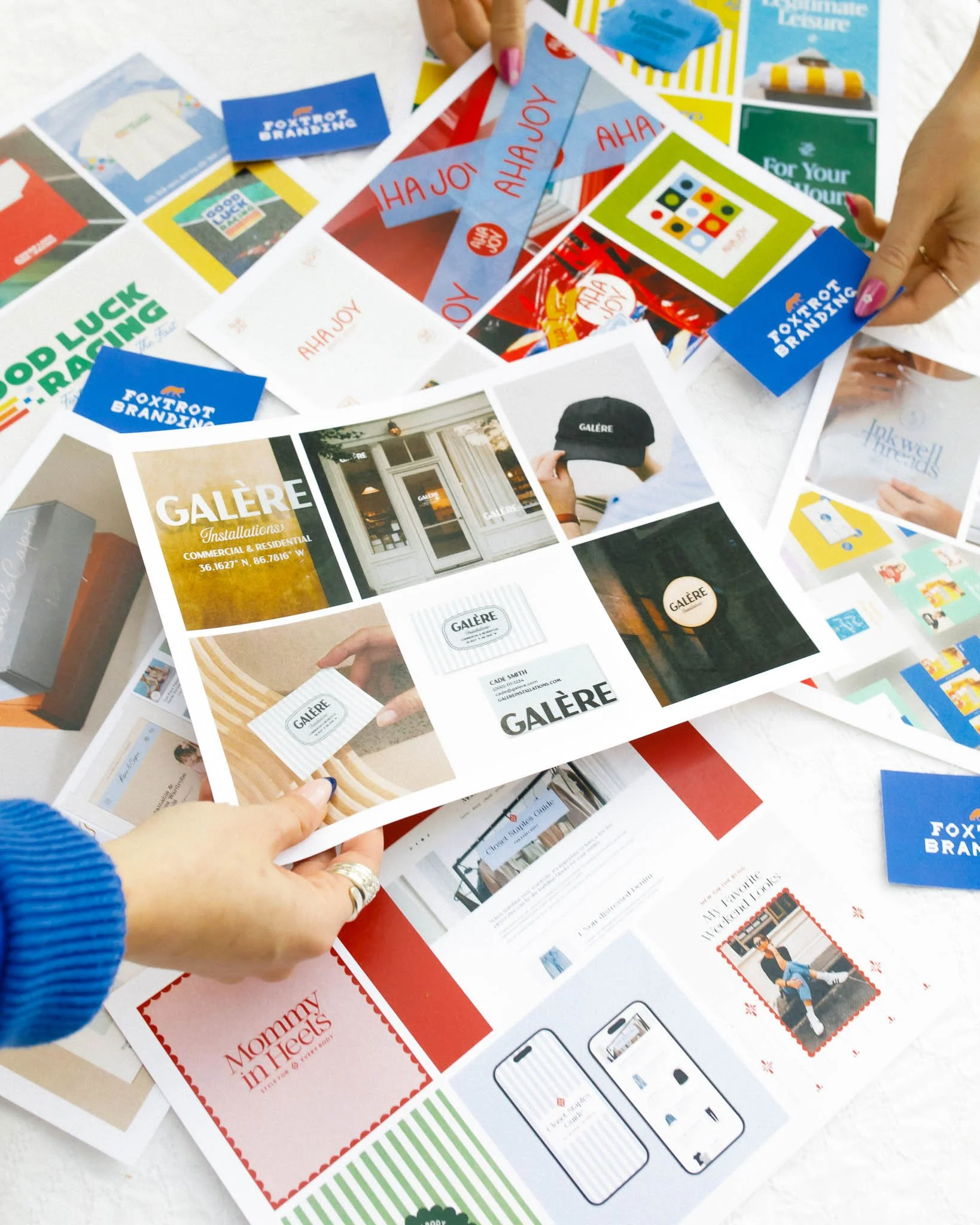 Top-down photo of sheets of paper with color branding printed on them and hand holding one paper