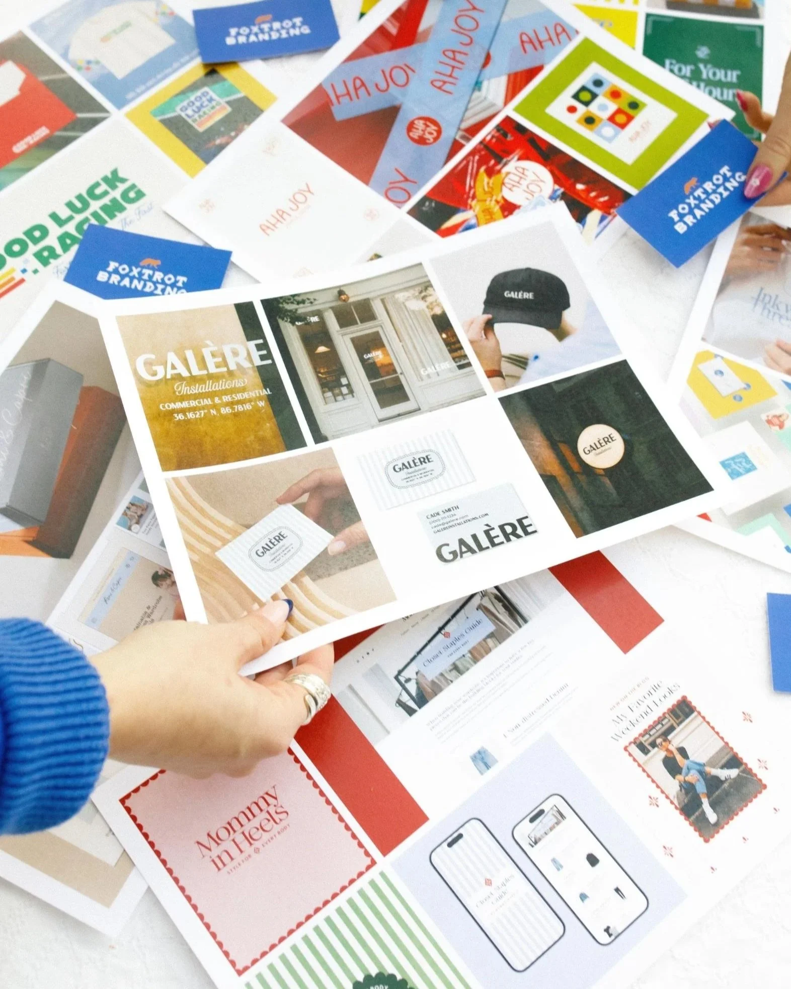 Top-down photo of sheets of paper with color branding printed on them and hand holding one paper
