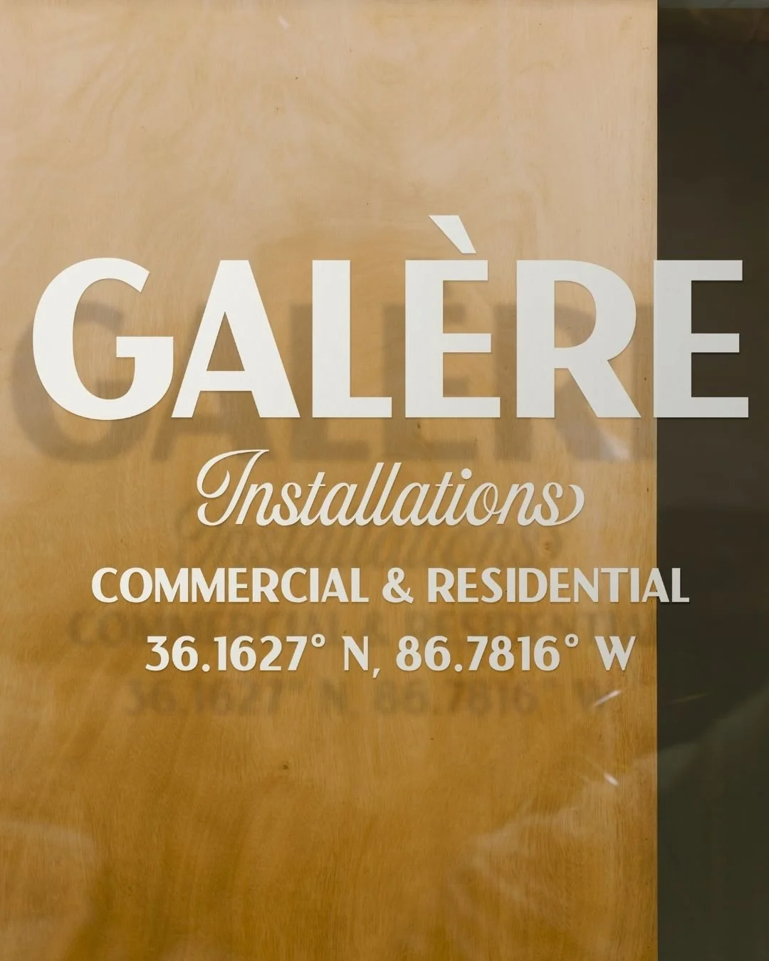 Galère installations logo design in etched glass on window with wood behind