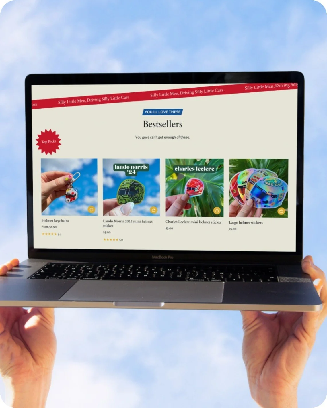 Hands holding computer with Good Luck Tess website with best sellers on screen