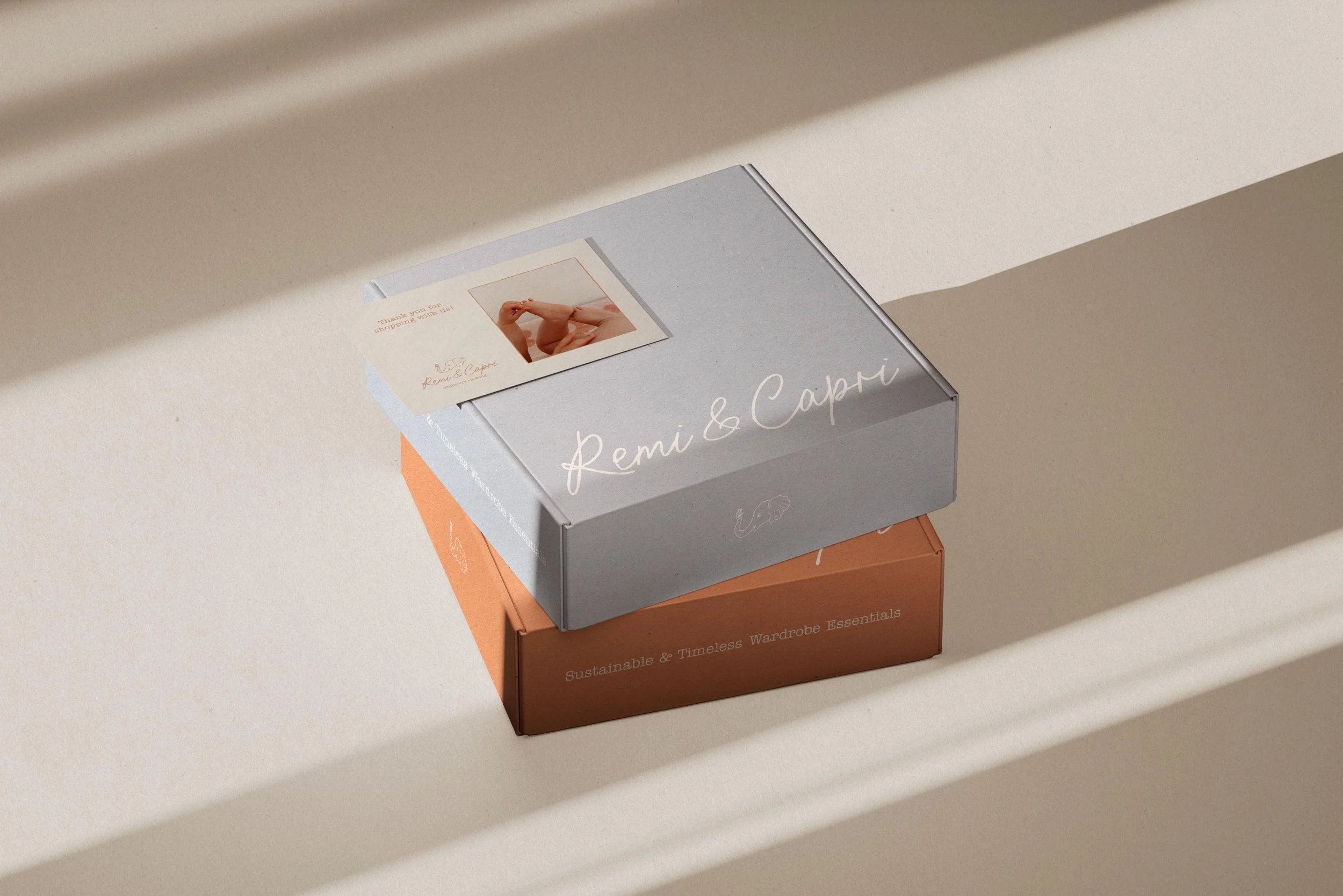 A blue mailer box and orange mailer box with "Remi & Capri" logos on them stacked on each other  with a branded insert card sitting on top