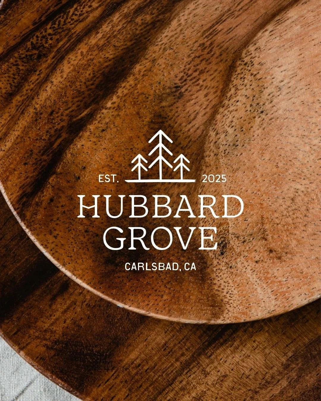 Hubbard Grove Logo design with tree icons over image of wood cutting boards