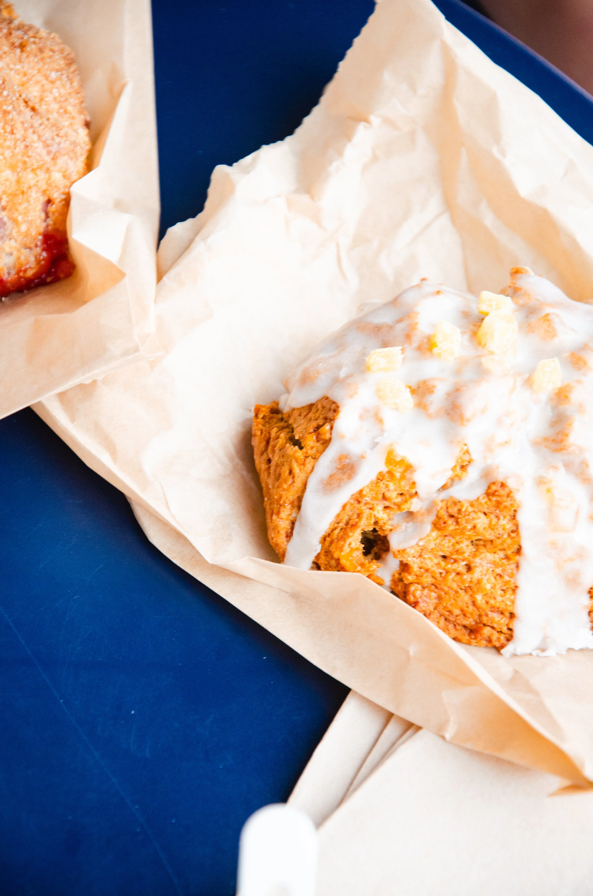 a sweet potato scone with maple frosting on a piece of wax paper