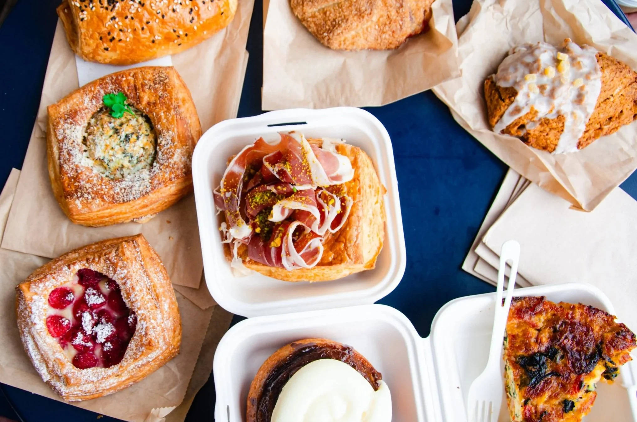 A royal blue table sets the background for 9 different kinds of colorful pastries.