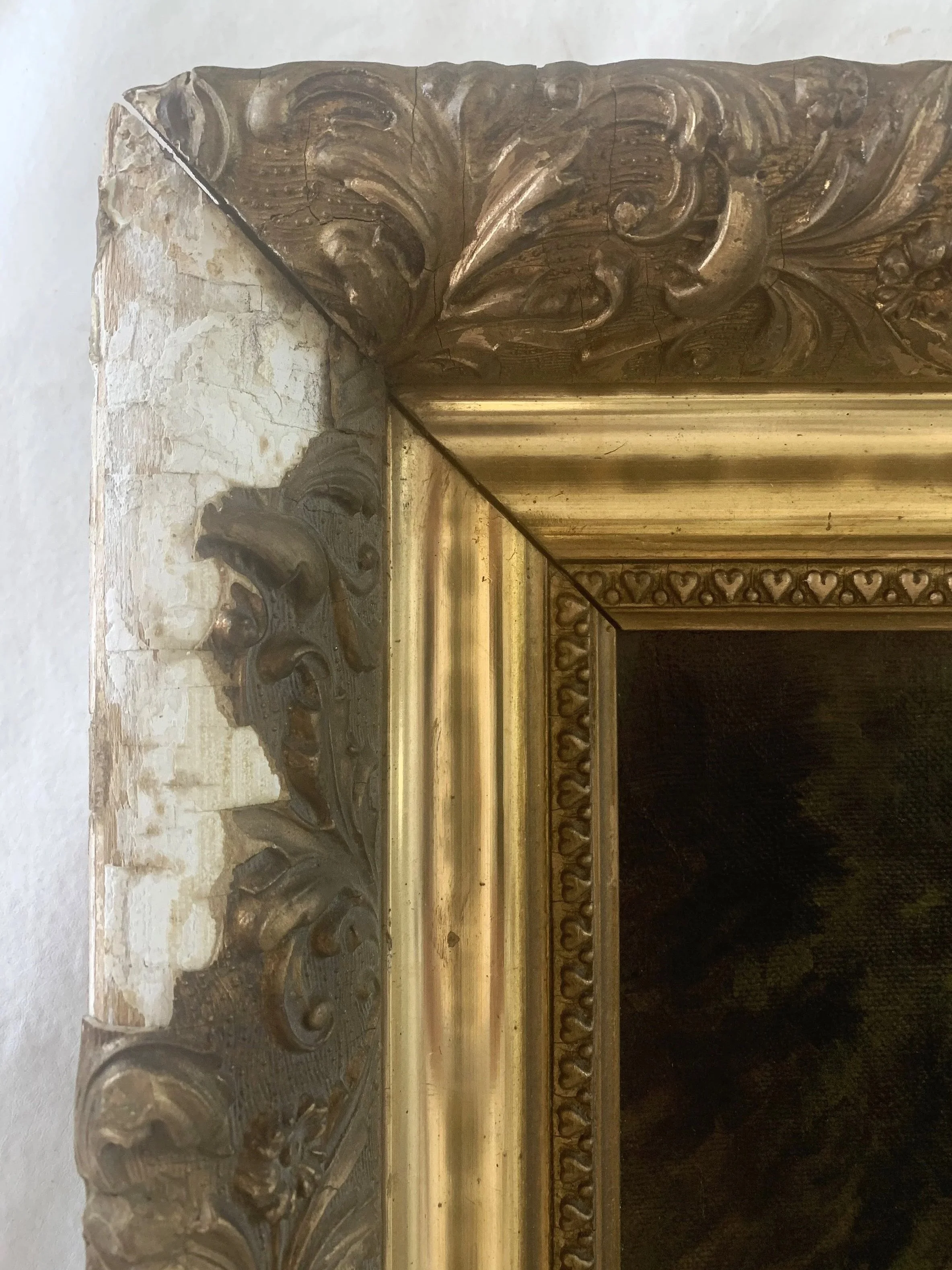 Close-up of an ornate, gilded fireplace mantel with intricate carved floral and foliage designs in gold and dark wood, showing weathered and chipped areas.
