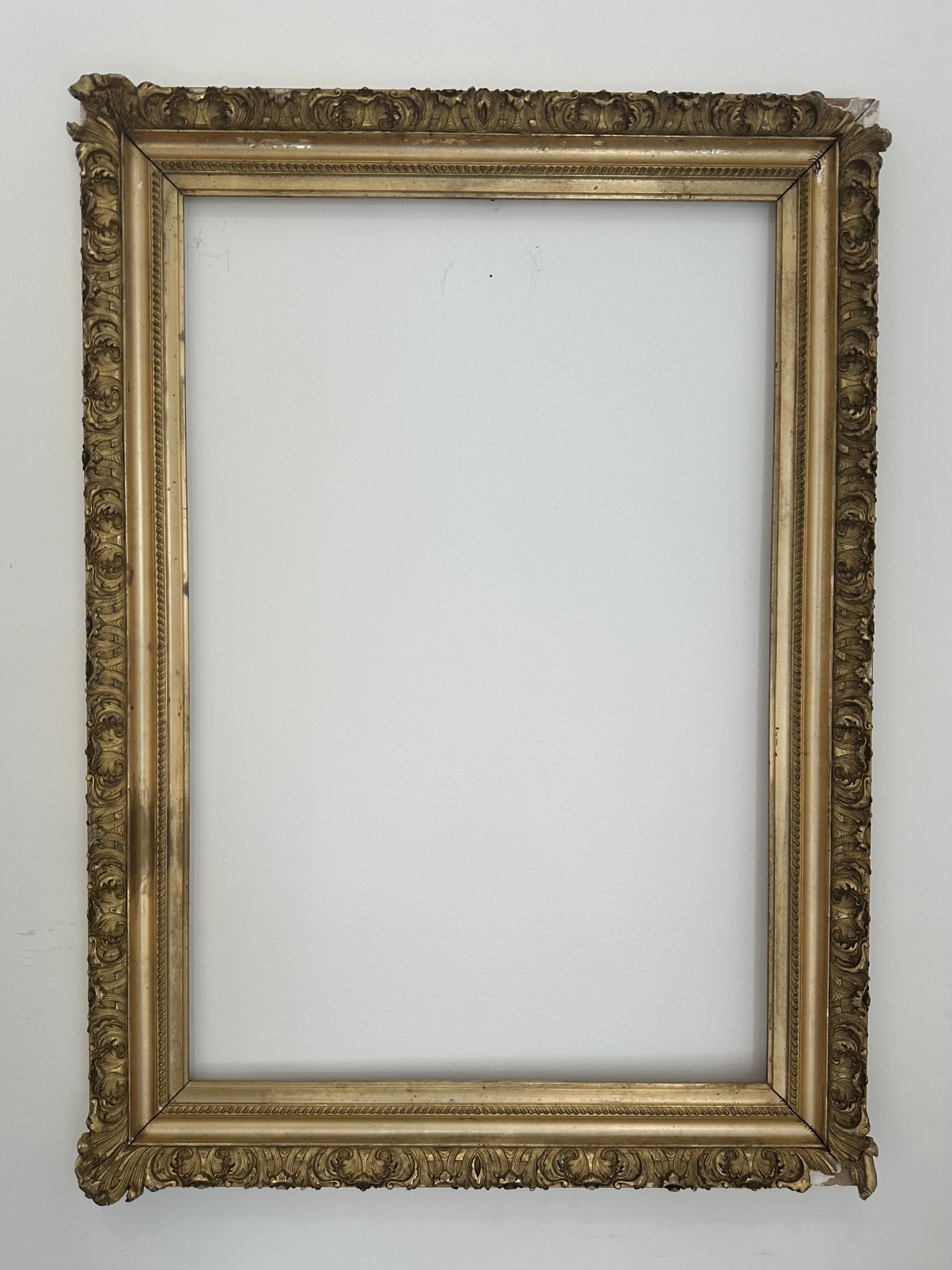 Empty ornate gold picture frame on a white wall