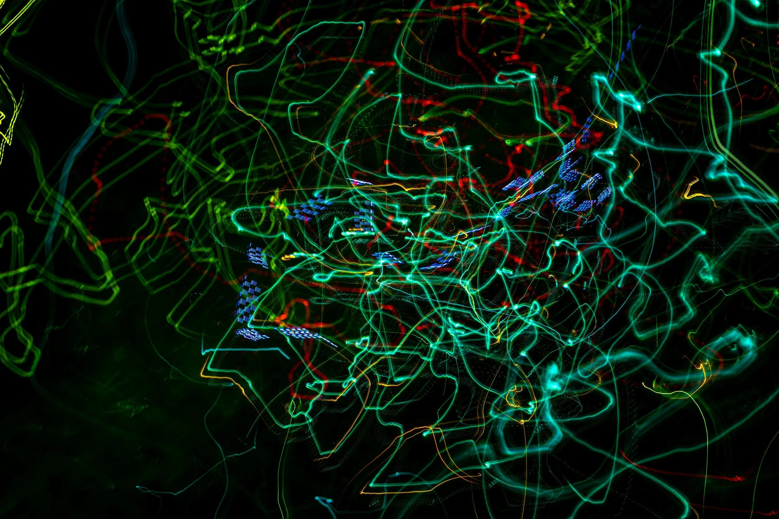 Colorful neon light trails on a black background, creating an abstract pattern.