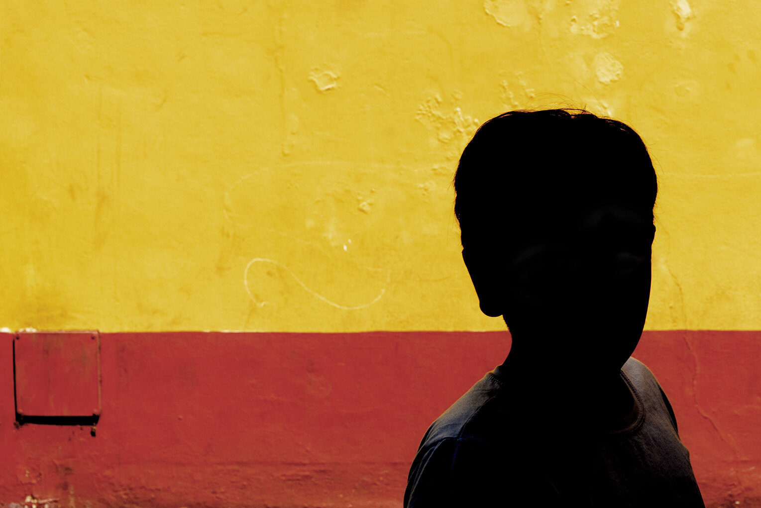 Silhouette of a person against a yellow and red wall.