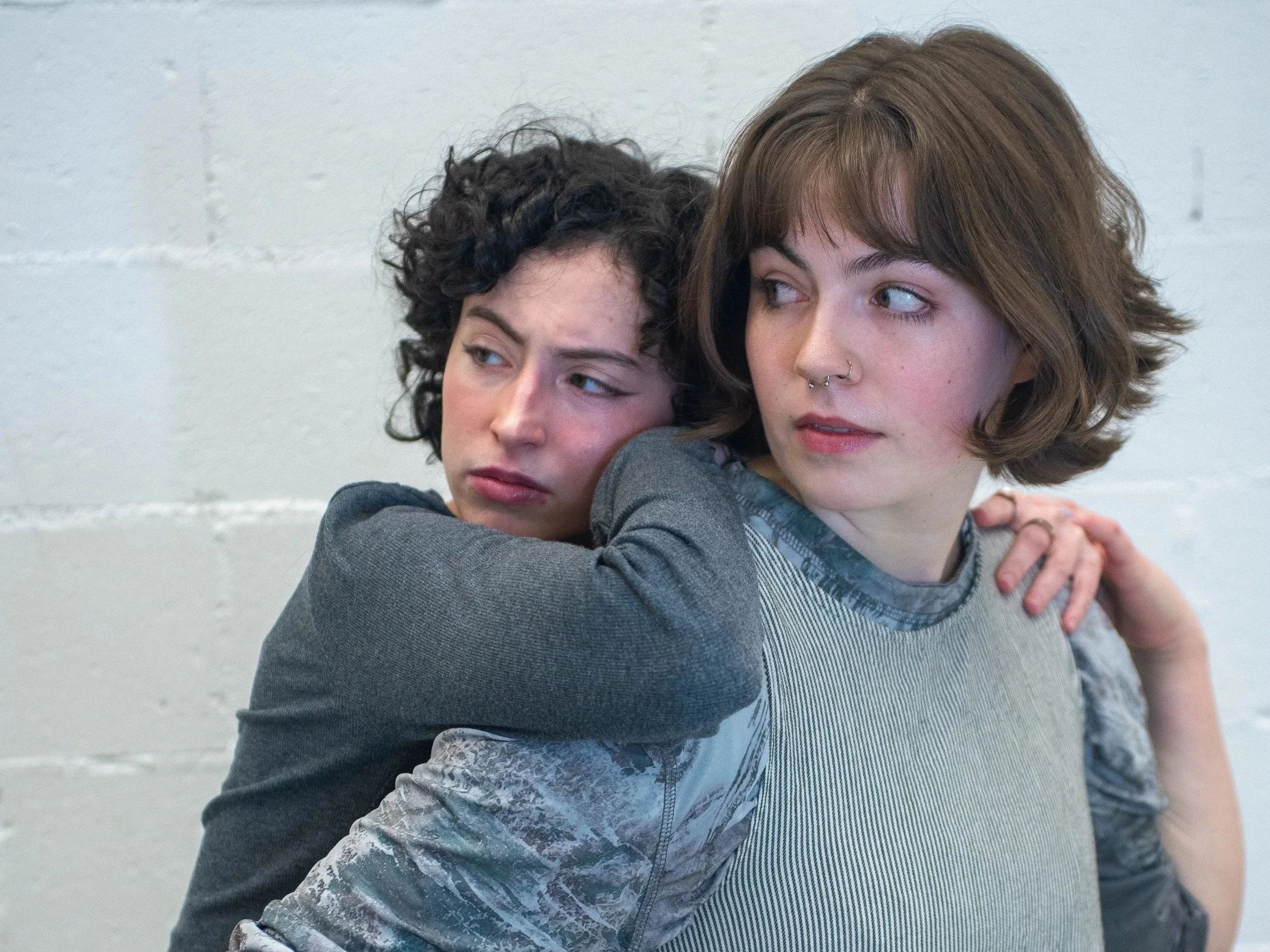 Two dancers holding onto one another looking into the corner.