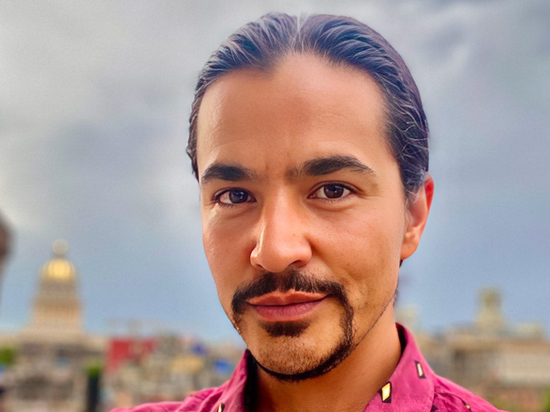 Ty Defoe looks at the camera against a blurred city backdrop.