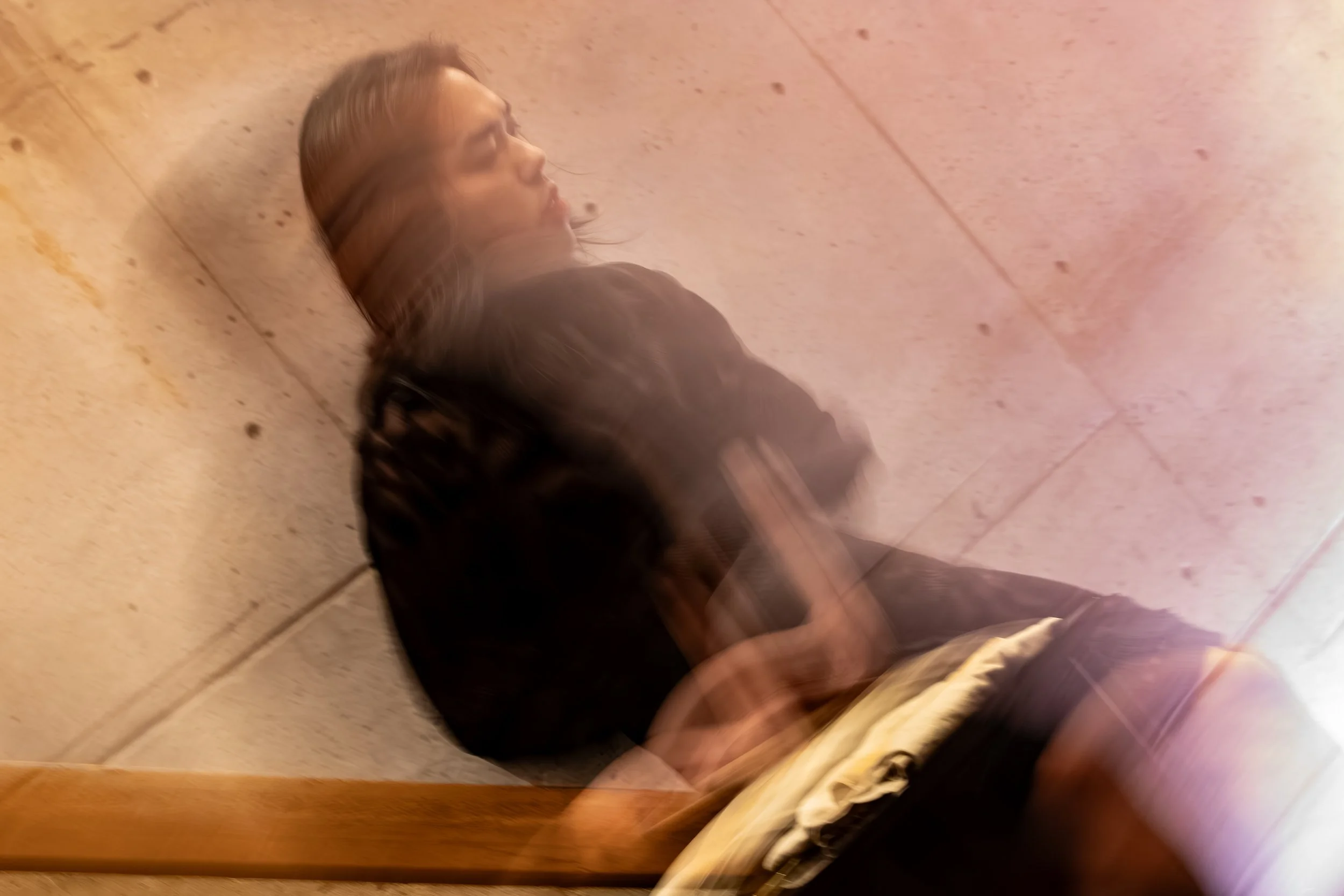 A blurry image of Anh Vo, in a black dress, sitting perched on top of a banister.