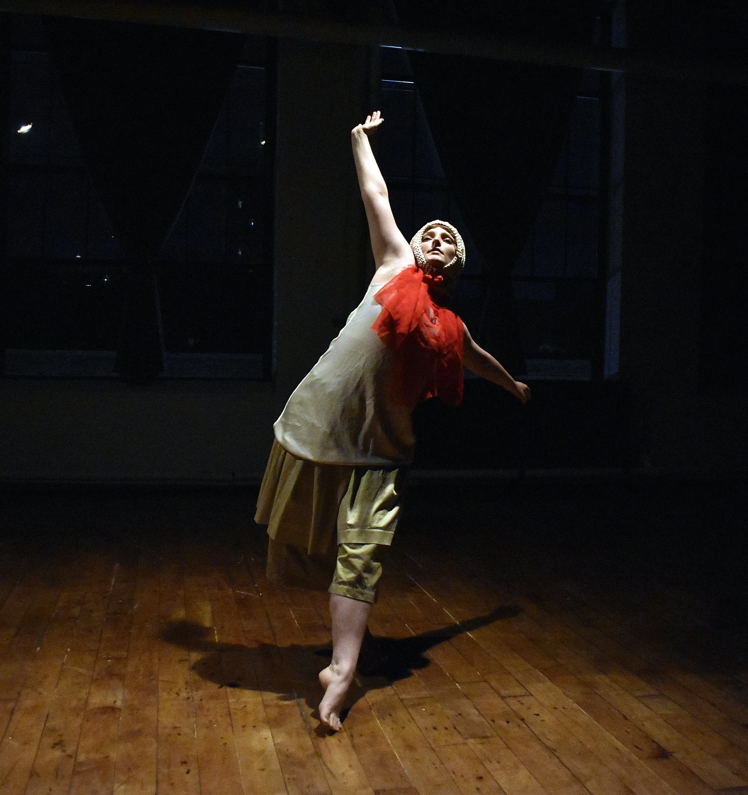 Lulu Munteau dances on a hardwood floor in a white knitted cap and a red ribbon.