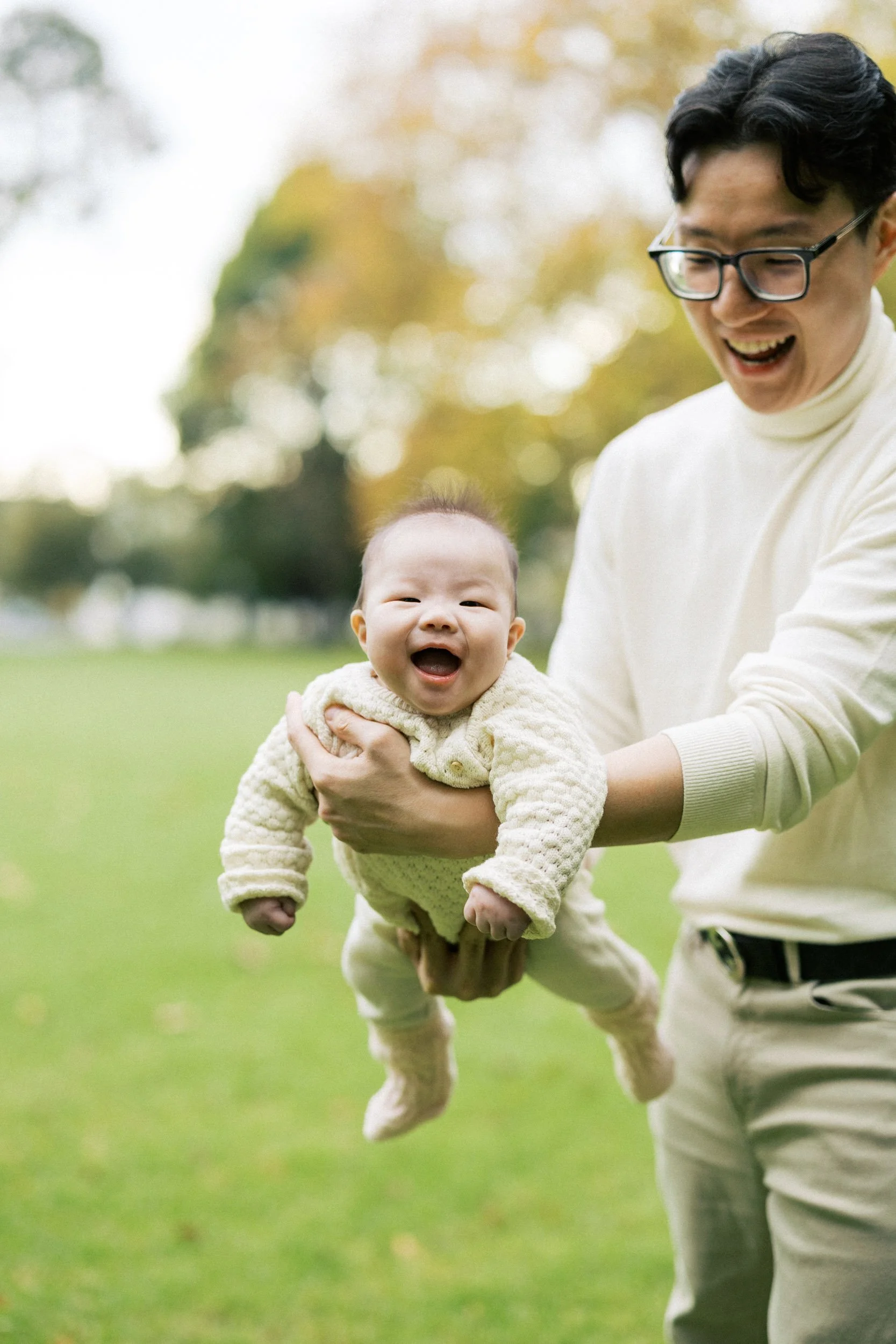 A smiling baby at Carlton Gardens in Autumn