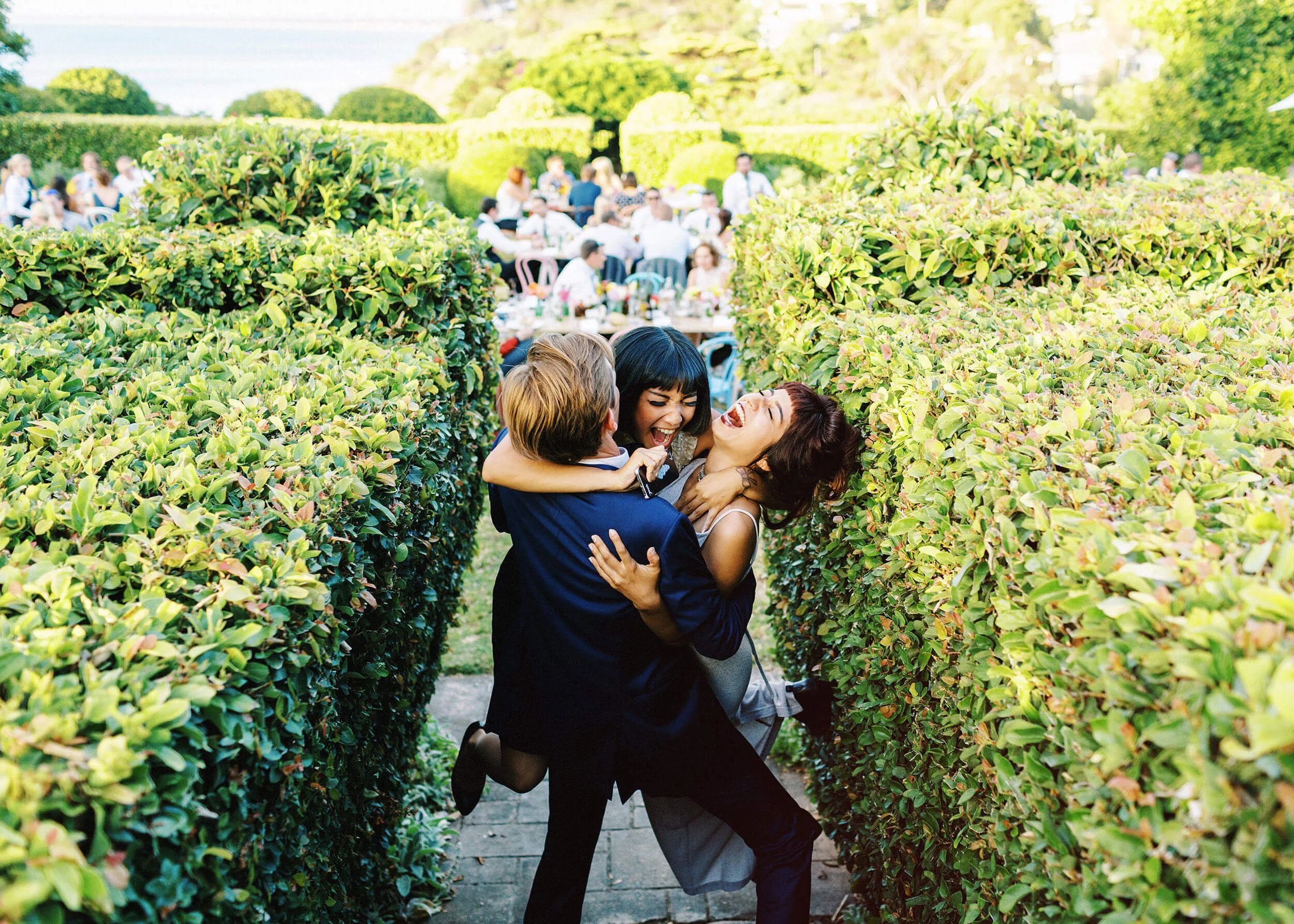 A candid photograph of two friends hugging the groom in a garden wedding in Mornington Peninsula