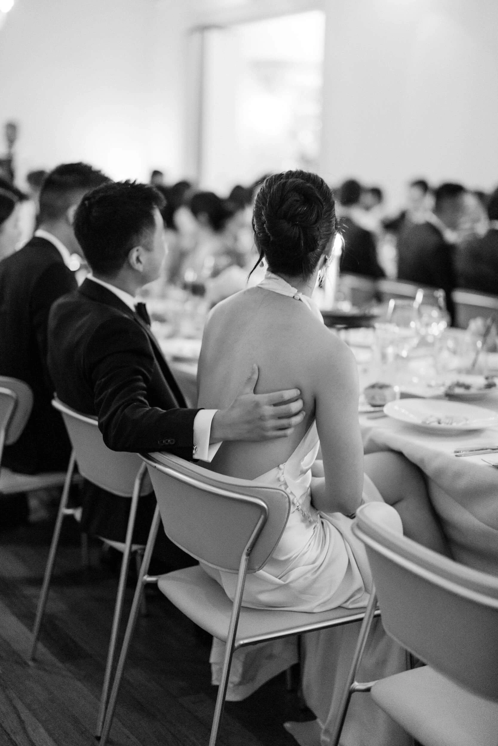 A bride and groom sit together at their reception at Sophia at the Prahran Arcade as the groom gently rests a hand on her back