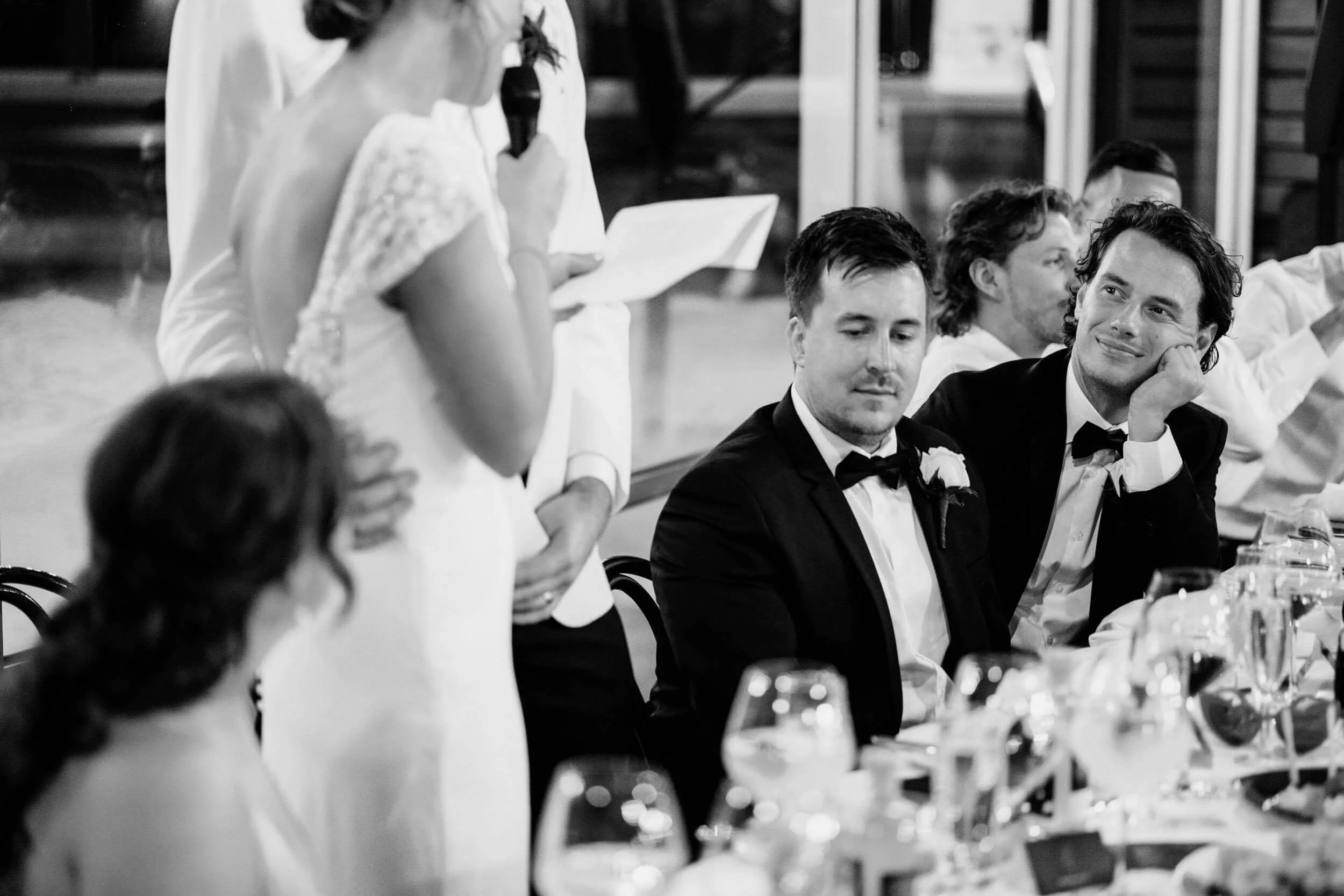 A groomsman listens intently and smiles during a speech during the bride's speech at the reception at Zonzo Estate.