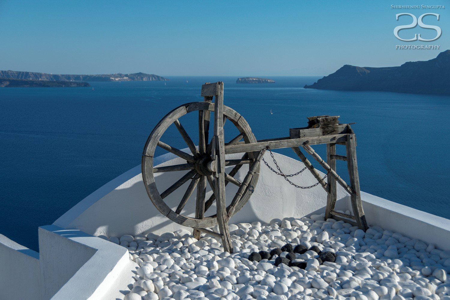 wooden wheel near white houses church blue domes oia imerovigli firostefani fira village santorini greece caldera volcanic island