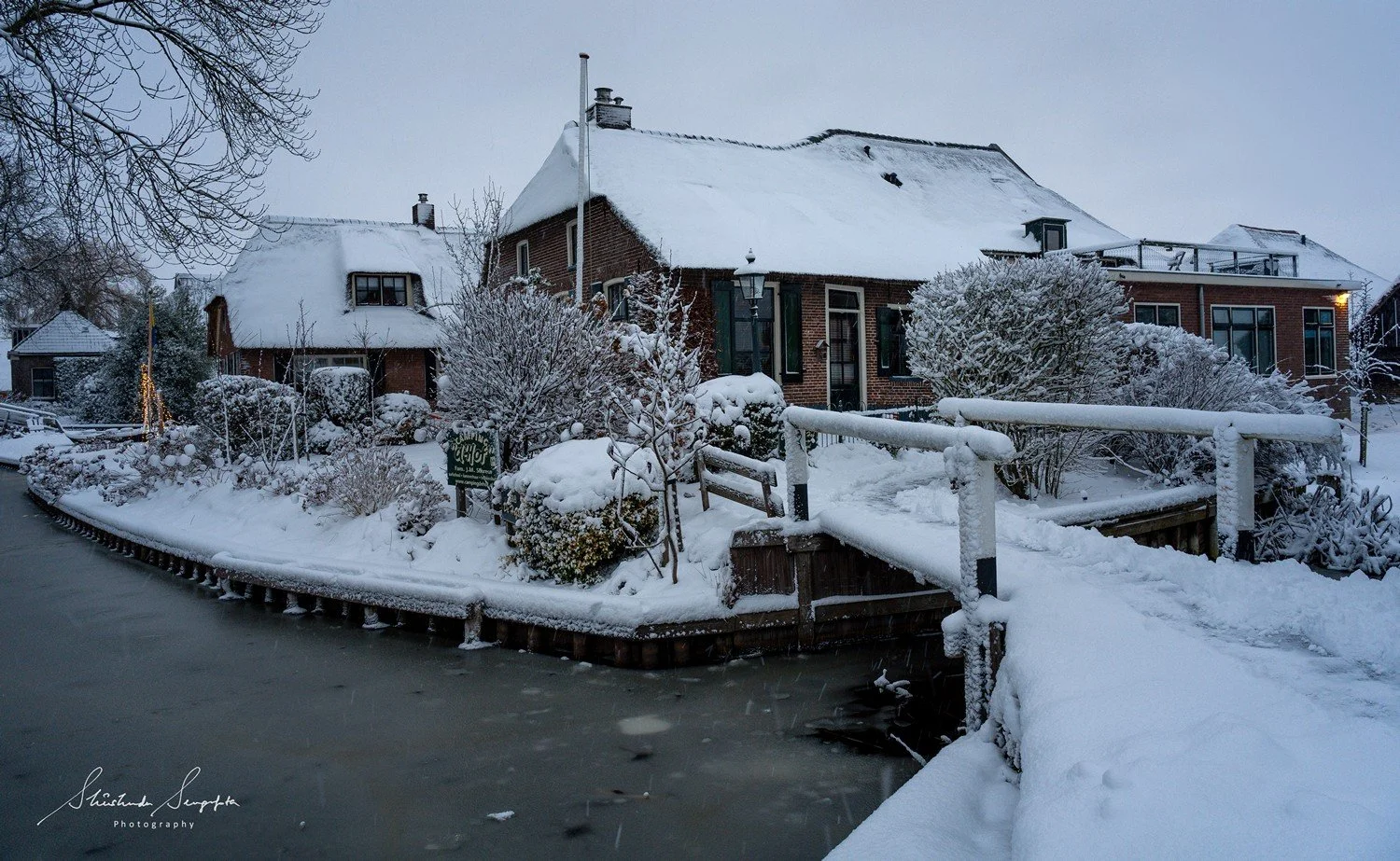 winter snowfall in giethoorn venice of the north with wooden houses thatched roof bridges canal reflection boats in overijssel netherlands holland shot at sunset during golden hour