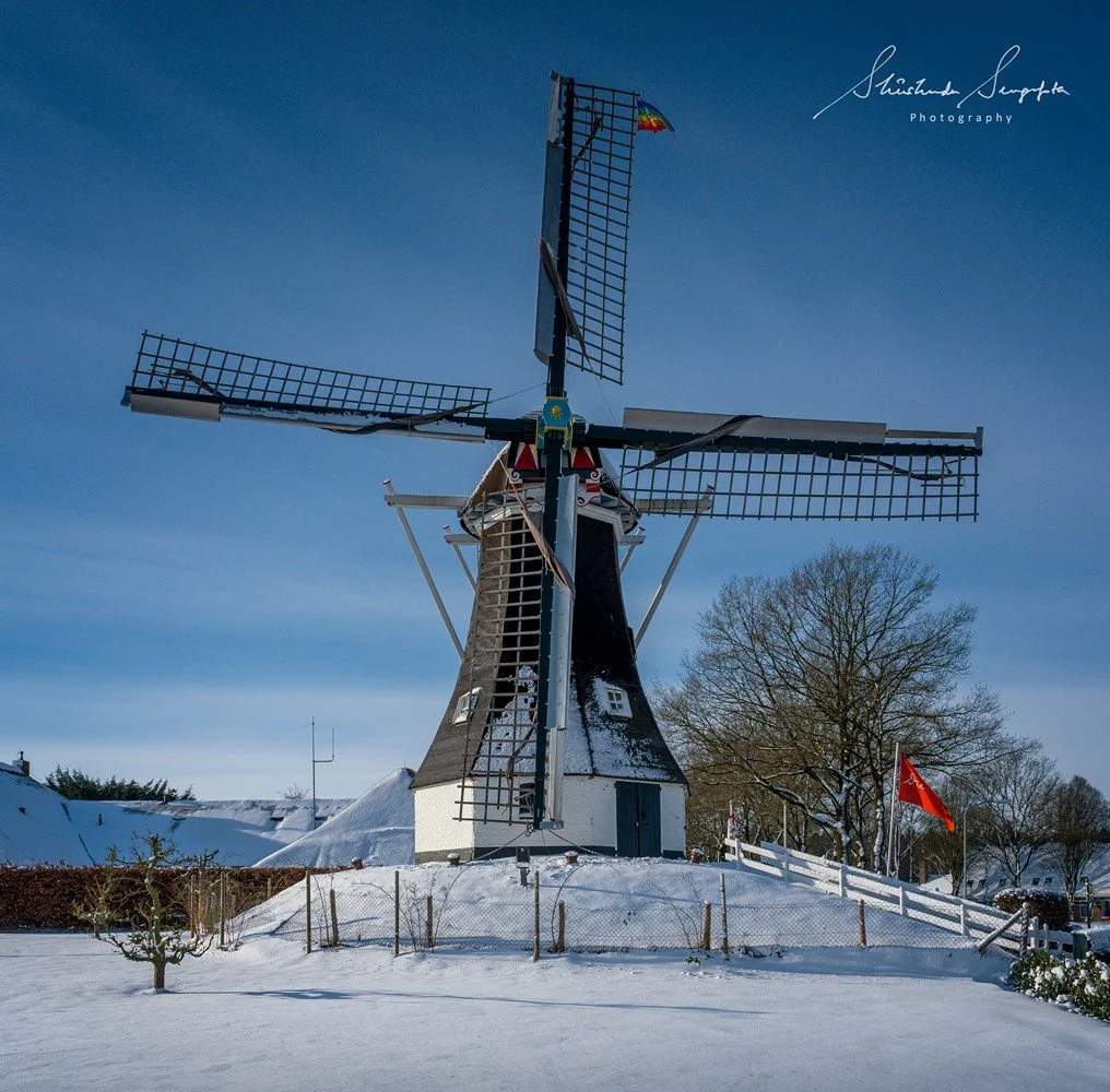 snow around village houses windmills and farms near dolmen hunebedden drenthe netherlands at sunset