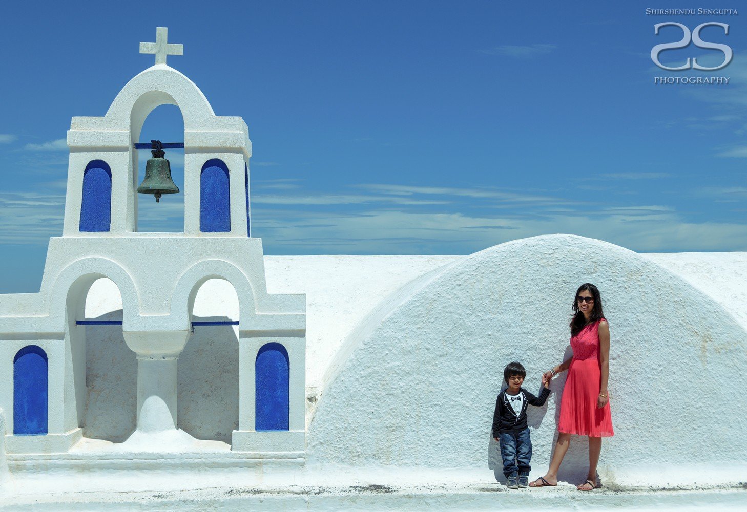 boy and lady standing near white houses church bell towers blue domes oia imerovigli firostefani fira village santorini greece caldera volcanic island
