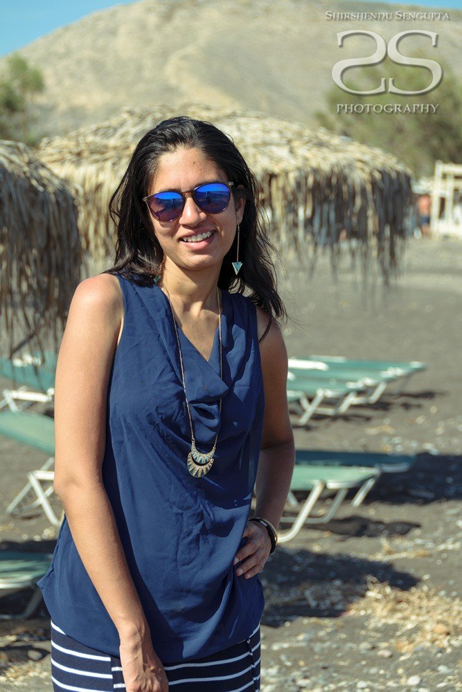 lady standing at black beach kamari perissa perivolos in satorini island greece