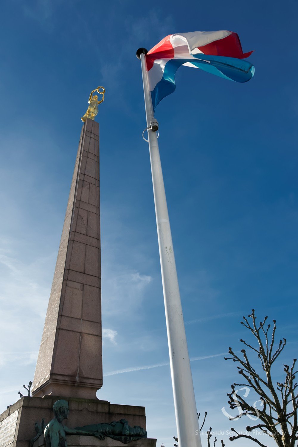 gelle fra monument of remembrance showcasing golden statue of woman holding crown atop obelisk near flag of luxembourg in luxembourg city