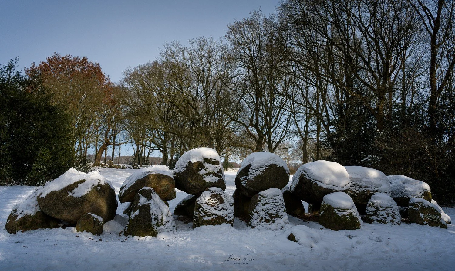 snow around village houses windmills and farms near dolmen hunebedden 18 drenthe netherlands at sunset