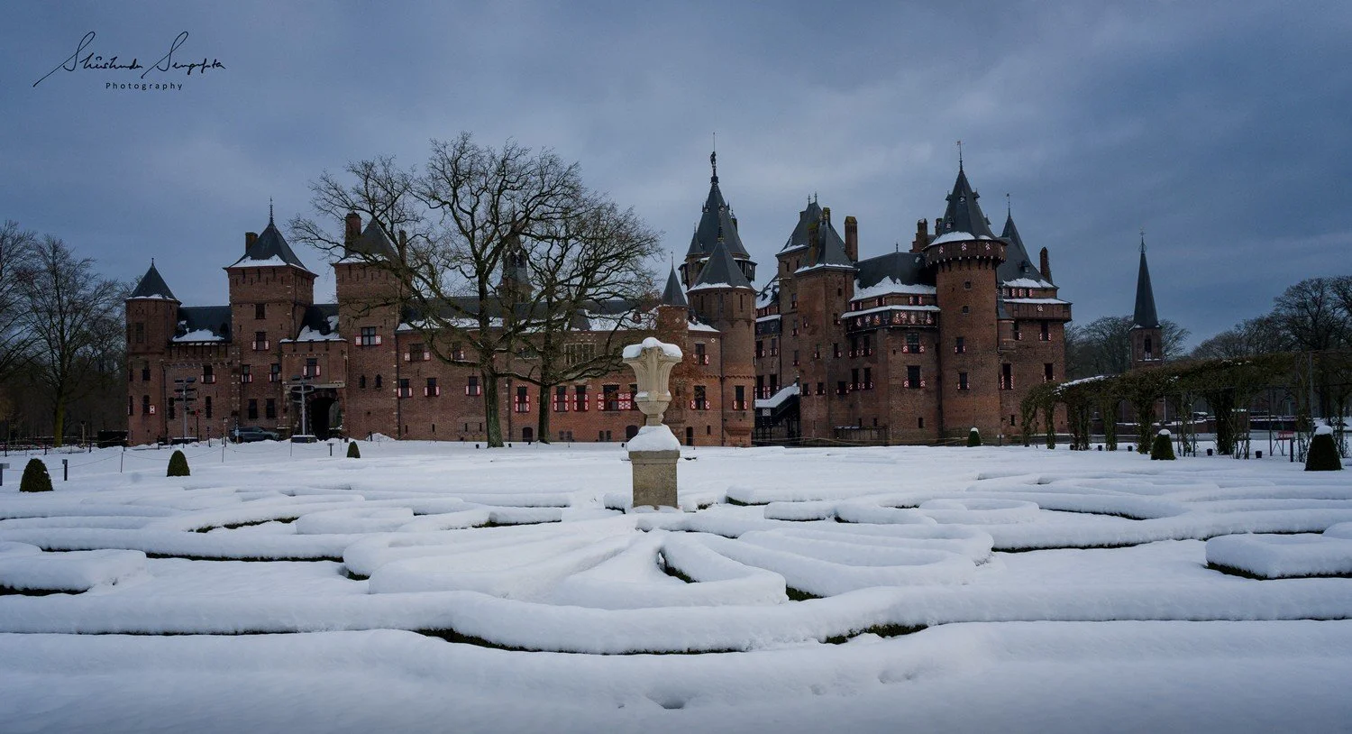 snow in gothic architecture of brick castle with moat marble fountain maze red white flowers and garden kasteel de haar in haarzuilens utrecht netherlands holland