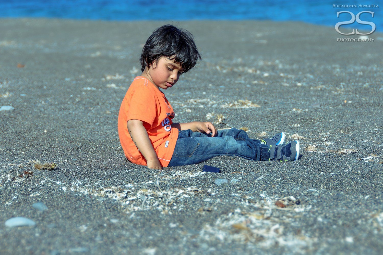 boy sitting at black beach kamari perissa perivolos in satorini island greece