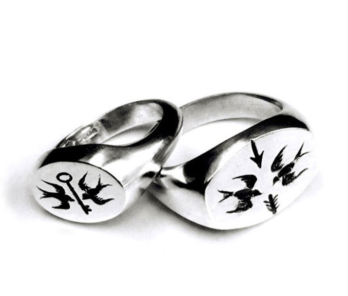 Two silver rings with engraved sailboats and tree designs.