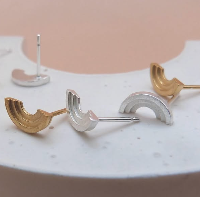 Gold and silver crescent-shaped earrings displayed on white marble surface.