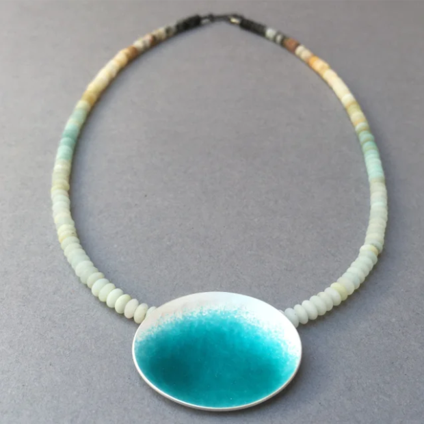 Beaded necklace with a large oval blue and white pendant on a gray background.
