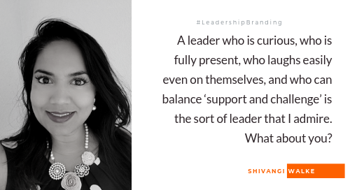 Black and white headshot of a woman with dark hair, smiling, wearing a necklace and a polka dot top, accompanied by a quote about leadership qualities.