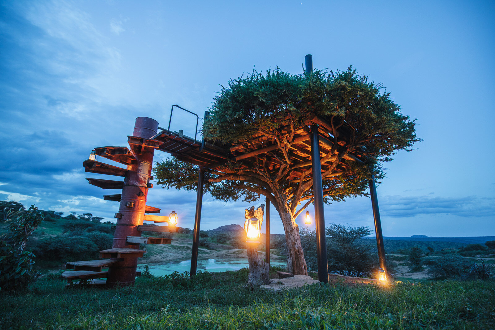 Opplyst trehus med tretrapp ved Ol Malo i Kenya, for en natt tett på naturen under safarien.