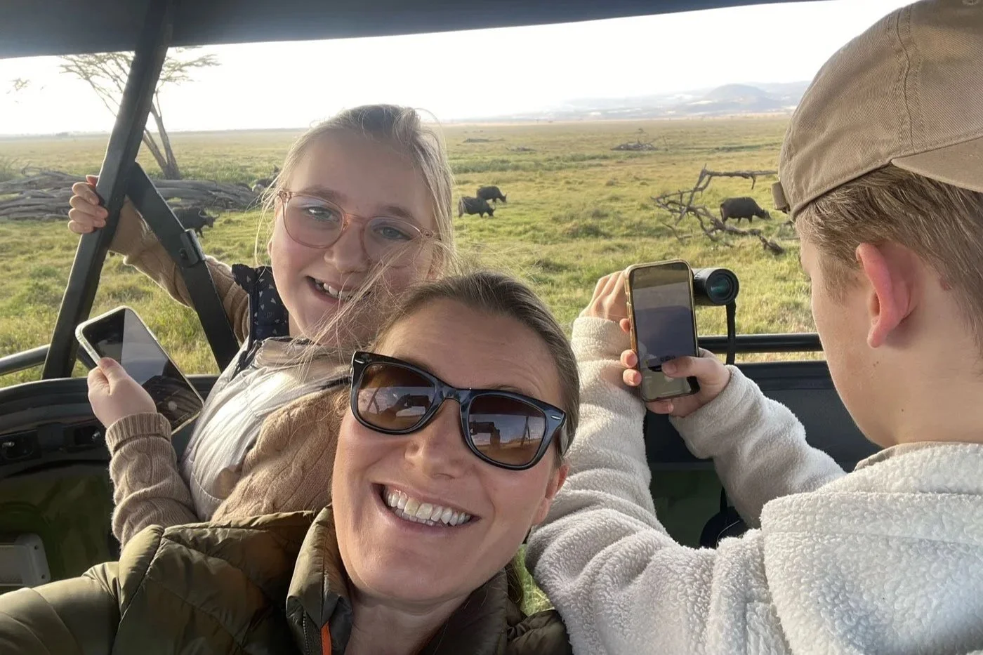 Familie på safari i Afrika, smilende i åpen safari-bil