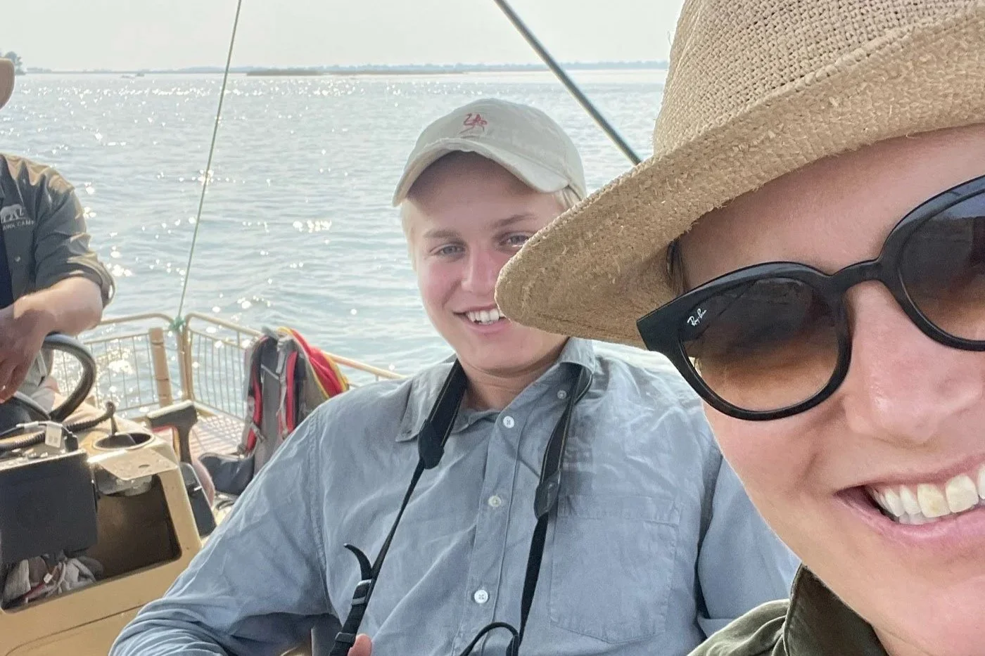 Ung gutt på båtsafari i Afrika med kikkert og caps