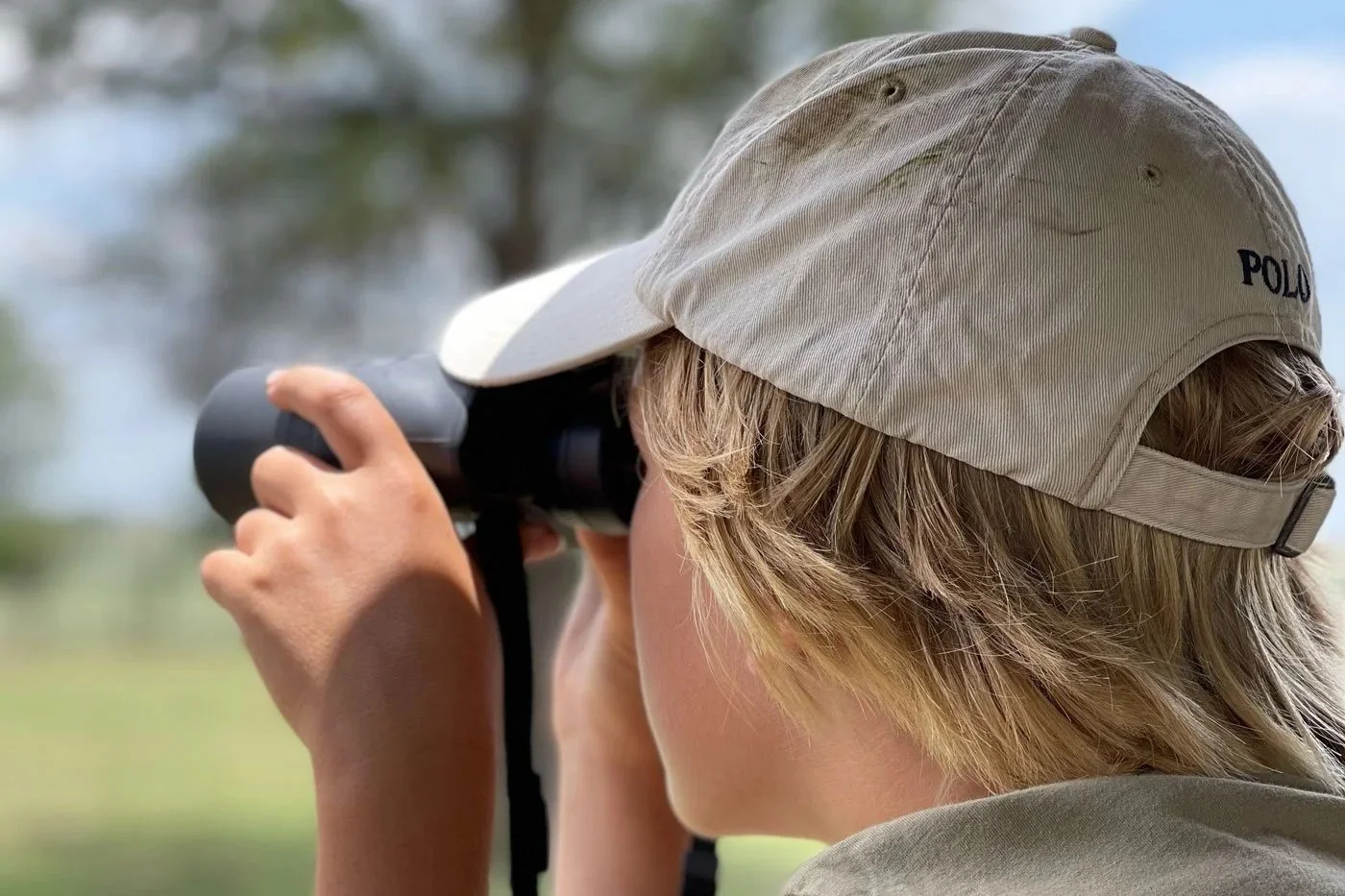 Barn på safari i Afrika med caps og kikkert, fokusert på dyreliv