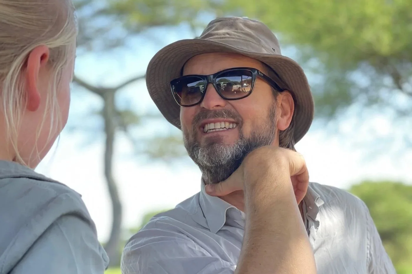 Mann på safari i Afrika med hatt og solbriller, ute i naturen