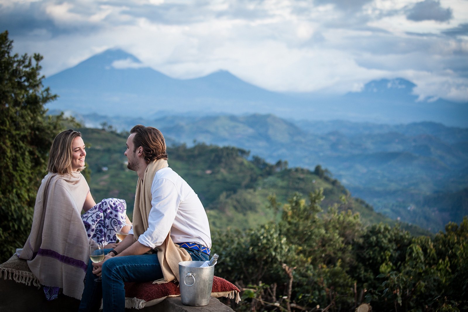 Par som nyter utsikt over fjellandskap i Uganda ved solnedgang