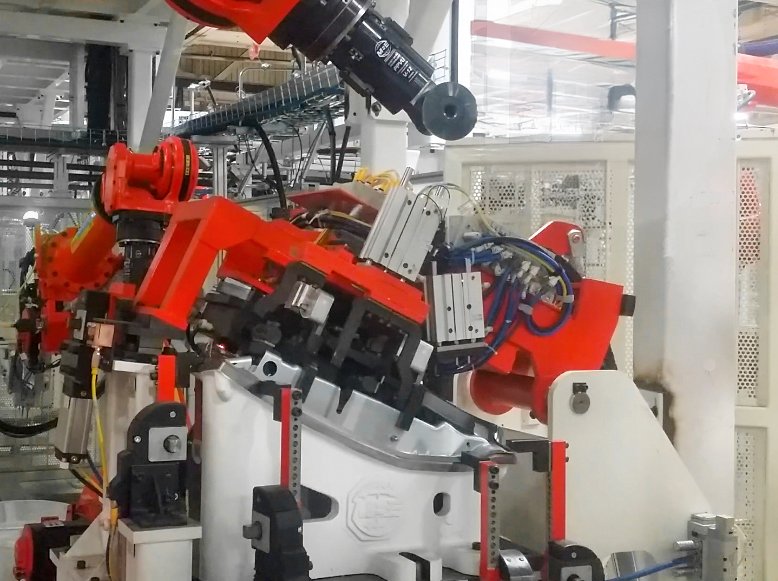 Automated manufacturing fixture positioning an automotive fender panel for robotic assembly.