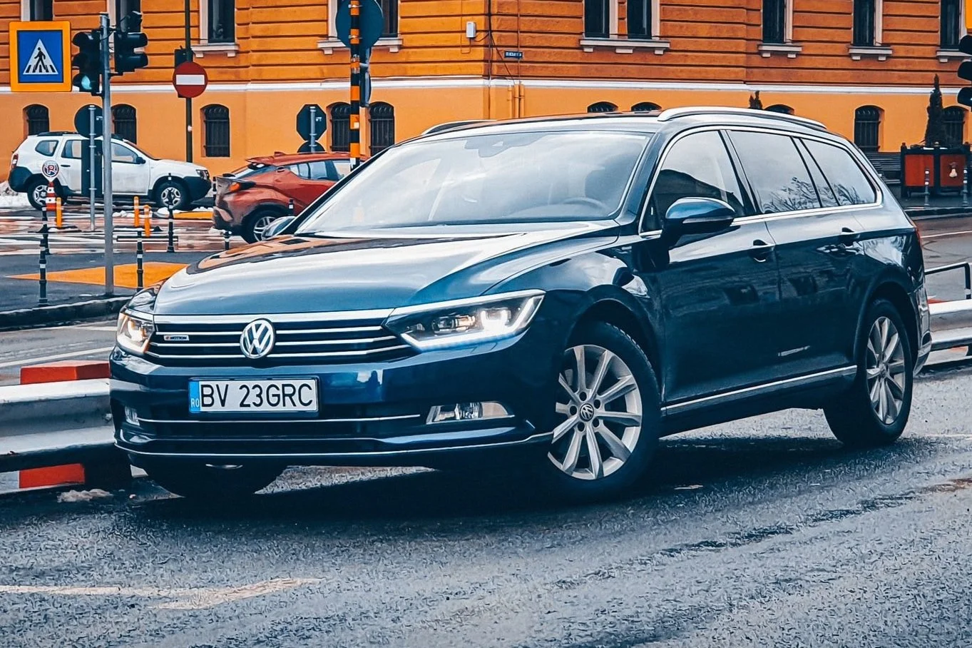 Mörkblå Volkswagen bil parkerad vid trottoarkant i stadsmiljö.