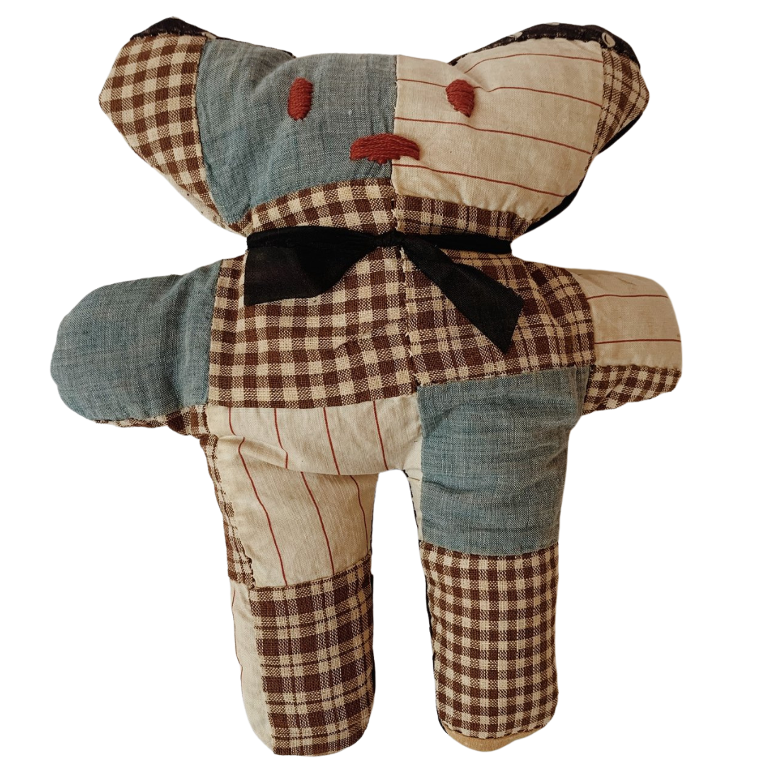 Patchwork teddy bear with various fabric patterns and colors, including plaid and striped designs, and a black bow.