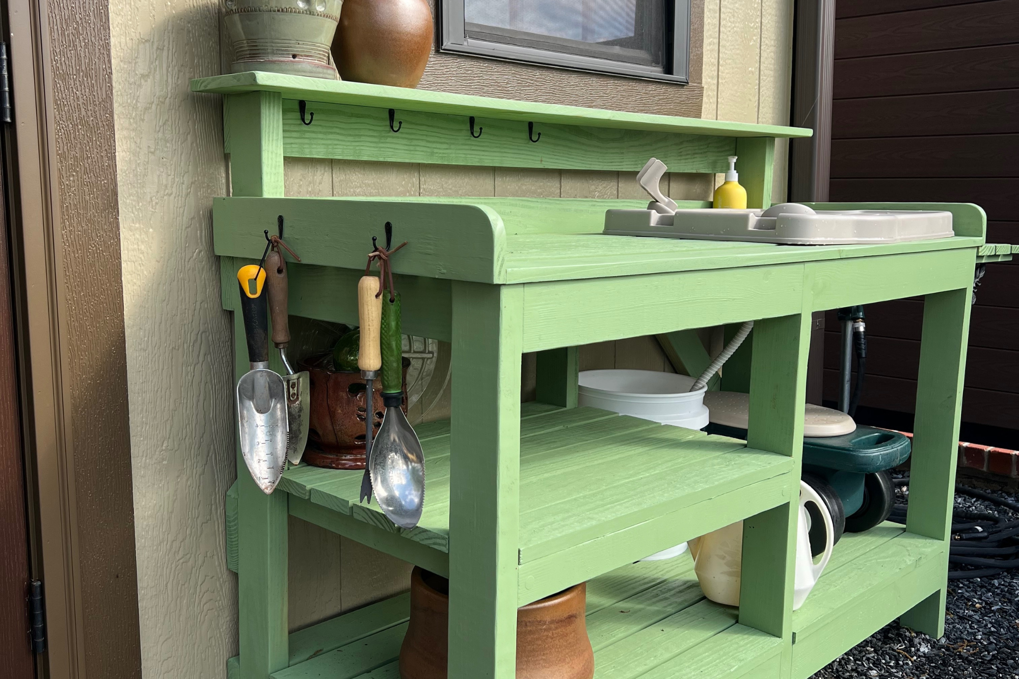 Potting bench with integrated sink and tool storage installed adjacent to a residential kitchen garden.